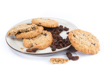 oatmeal raisin cookies on a plate with loose raisins isolated on white