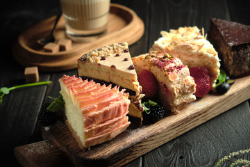 Different pieces of cakes on a wooden board . catering menu