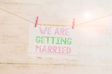 Writing note showing We Are Getting Married. Business concept for Engagement Wedding preparation Loving couple Clothesline clothespin rectangle shaped paper reminder white wood desk