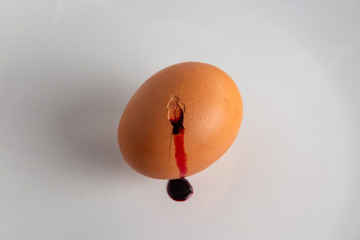 animal food rejection concept: blood flows from a cracked colored egg, short focus