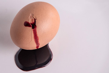 animal food rejection concept: blood flows from a cracked colored egg, short focus
