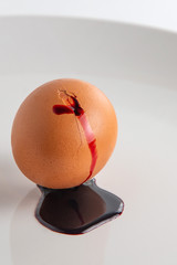 animal food rejection concept: blood flows from a cracked colored egg, short focus