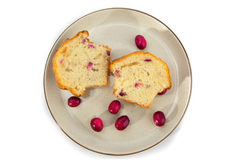 overhead view of a cranberry lemon muffin with raw cranberries cut in half on a plate isolated on white