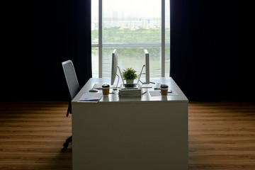 Empty modern office room with desk and two computer monitors on it but only one chair