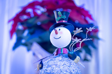 Holiday snowman table decoration in front of a holiday wreath