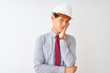Chinese architect man wearing tie and helmet standing over isolated white background thinking looking tired and bored with depression problems with crossed arms.