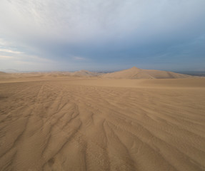Fototapeta na wymiar tire tracks over the sand at Ica desert, dunes in the horizon