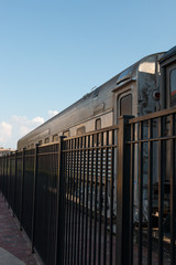 Fototapeta na wymiar Train Car Behind Fence on a Sunny Afternoon