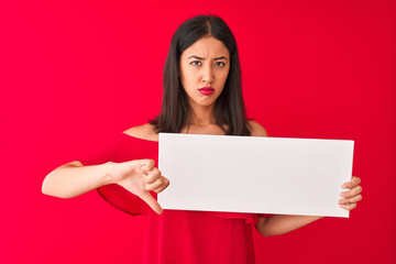 Fototapeta premium Young beautiful chinese woman holding banner standing over isolated red background with angry face, negative sign showing dislike with thumbs down, rejection concept