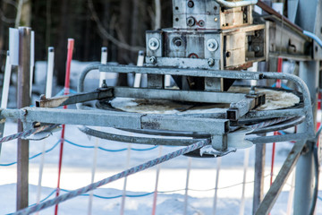 A mechanism of the ski lift. Rotating wheel of elevator on snowy hill.