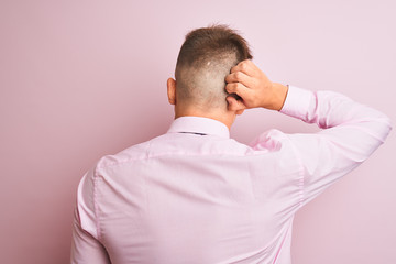 Young handsome businessman wearing shirt and tie standing over isolated pink background Backwards thinking about doubt with hand on head
