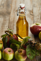bottle of fresh cider near apples on wooden surface