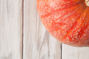 one large bright red pumpkin in the top corner of the image on a white wood textured background top view