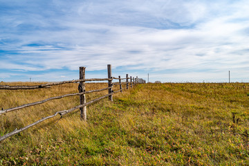 A pasture for horses with a long fence stretching beyond the horizon