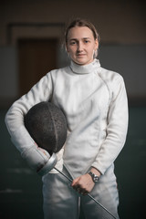 A young woman fencer standing in the school gym
