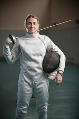 A young woman fencer standing in the school gym with a sword behind her back