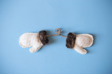 Christmas mood flat lay. Happy New Year flat lay on the paper. White woolen mittens with brown fur on blue paper.