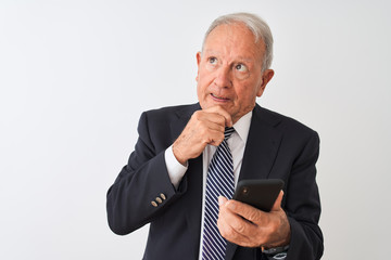 Senior grey-haired businessman using smartphone standing over isolated white background serious...