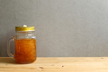 Citron tea in a glass bottle on wooden table with gray background