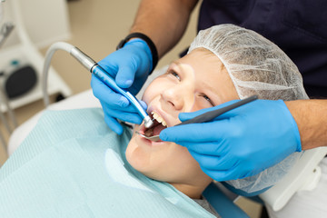 Adult doctor uses stomatological drill and mirror in his operation