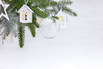 Fototapeta na wymiar festive winter holidays background. christmas tree branch decorated with glass ball, wooden decorative toy houses garland and star