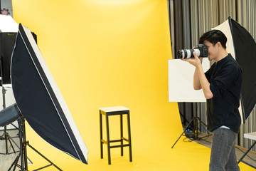 Young  Professional photographer with camera in on photo studio background.