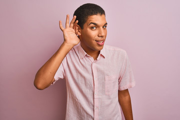 Young handsome arab man wearing casual shirt standing over isolated pink background smiling with hand over ear listening an hearing to rumor or gossip. Deafness concept.