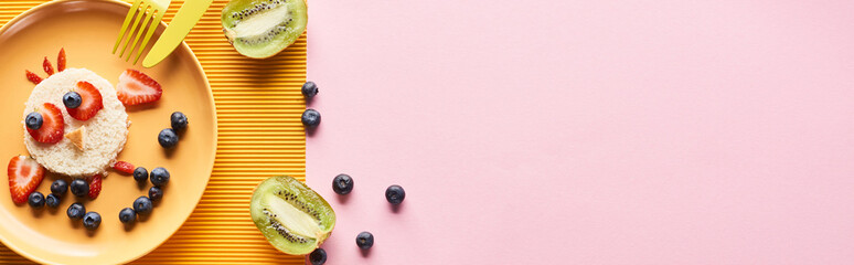 top view of plate with fancy animal made of food for childrens breakfast near cutlery on yellow and pink background