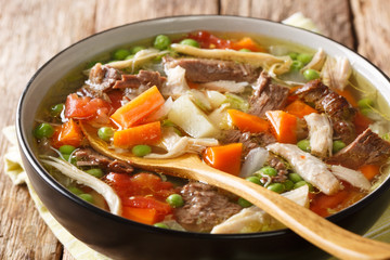 Thick slowly cooked soup with vegetables and meat close-up in a plate. horizontal