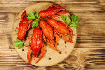 Boiled crayfish on cutting board on wooden table. Top view