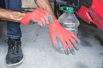 Man wearing red protective gloves in garage.
