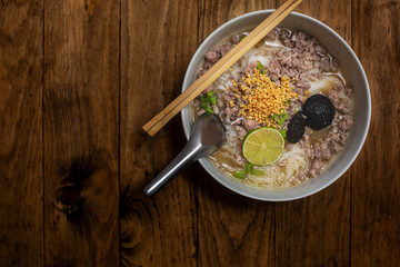Noodles top view wooden background texture Noodles soup Spicy TOM YAM pork noodle soup with lemongrass chilly pasted and lime juice ground beans White bowl Peanut Sweet and sour taste. copy space food