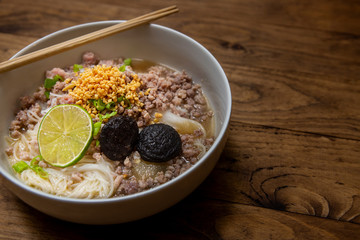 Noodles top view wooden background texture Noodles soup Spicy TOM YAM pork noodle soup with lemongrass chilly pasted and lime juice ground beans White bowl Peanut Sweet and sour taste. copy space food