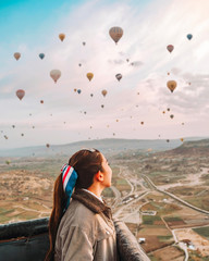 Asian woman watching colorful hot air balloons flying over the valley at Cappadocia, Turkey This...