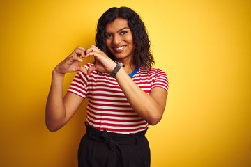 Transsexual transgender woman wearing stiped t-shirt over isolated yellow background smiling in love showing heart symbol and shape with hands. Romantic concept.