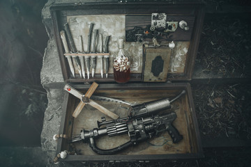 A set of things hunter evil spirits, demons, vampires in an old suitcase. An old book with spells, aspen stakes, tincture of garlic and Holy water, rosary, cross and gun. The view from the top.
