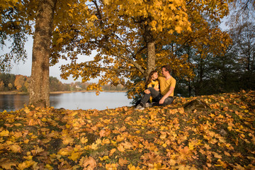 Young couple on lake coast. Sunny Autumn Day.
