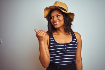 Obraz na płótnie Canvas Beautiful transsexual transgender woman wearing summer hat over isolated white background smiling with happy face looking and pointing to the side with thumb up.