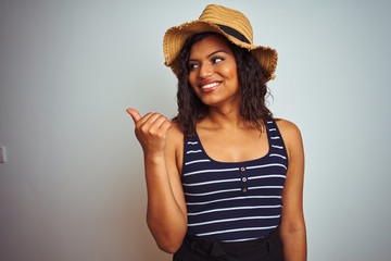 Beautiful transsexual transgender woman wearing summer hat over isolated white background smiling with happy face looking and pointing to the side with thumb up.