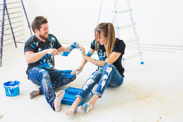People, renovation and repair concept - portrait of happy couple pour paint and having fun