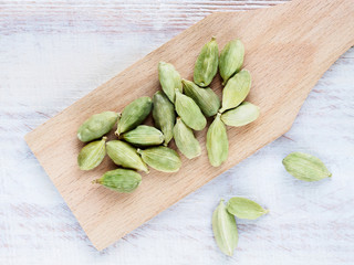 Spice Green cardamom (Elettaria cardamomum) on a spatula diagonally on a brown wooden background