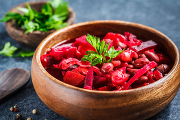 Vegetarian beetroot soup borsch with beans in a wooden bowl on blue background. Healthy vegetarian food concept.
