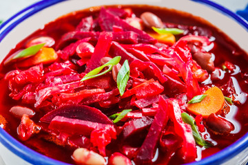 Vegetarian beetroot soup borsch with beans in white bowl on white background. Healthy vegetarian food concept.