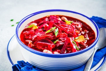 Vegetarian beetroot soup borsch with beans in white bowl on white background. Healthy vegetarian food concept.