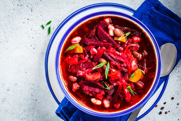 Vegetarian beetroot soup borscht with beans in white bowl on white background. Healthy vegetarian food concept.