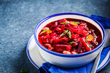 Vegetarian beetroot soup borsch with beans in white bowl on blue background. Healthy vegetarian food concept.