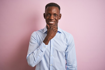 Obraz premium African american man wearing blue elegant shirt standing over isolated pink background looking confident at the camera with smile with crossed arms and hand raised on chin. Thinking positive.