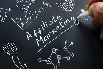 Man is writing Affiliate marketing on a black surface.