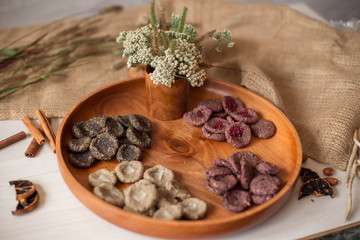 Assortment of sweets without sugar and gluten on a wooden dish. Dessert made from healthy natural ingredients. Beautiful composition of healthy diet candies and flowers