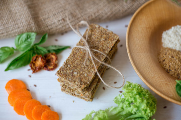 Crispbread tightened by a rope. Healthy food on a white background besid the ingredients in a wooden plate. .Lettuce with carrot near bread cakes